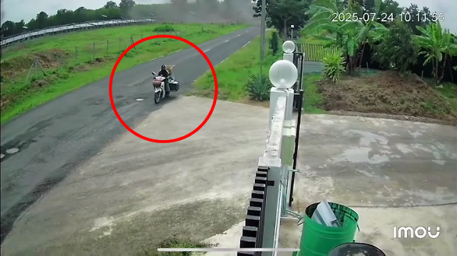 24일(현지시간) 태국 동부 수린주의 한 국경 마을에 캄보디아군이 쏜 것으로 추정되는 다연장로켓포가 떨어지는 와중에 한 오토바이 배달원이 연기를 뚫고 이동하고 있다. 2025.7.25. 페이스북 캡처