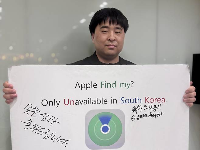 During an interview with The Korea Herald, Hwang Ho-chan holds one of the protest signs he used to raise awareness about the long-standing unavailability of Apple’s Find My feature in South Korea. (Moon Joon-hyun/The Korea Herald)