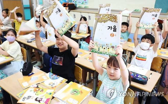 지난 2023년 오전 여름방학을 마치고 개학한 경기도 수원시 영화초등학교에서 2학년 학생들이 2학기 교과서를 보여주며 환하게 웃고 있다. [사진 출처 = 연합뉴스]