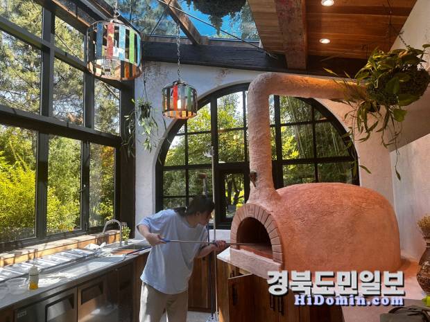 화덕에 피자를 굽기 위해 화덕 속으로 조심스럽게 밀어 넣는 모습에서 정성스러운 손길이 느껴진다. 사진=야생화 일기 제공