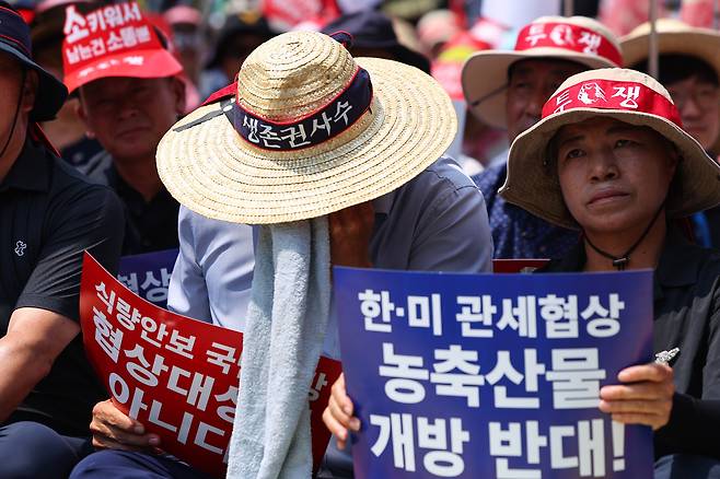 지난 28일 서울 용산구 삼각지역 인근에서 열린 한미 상호관세 협상 농축산물 개방 반대 결의대회에서 한 참가자가 수건으로 땀을 닦아내고 있다./연합뉴스