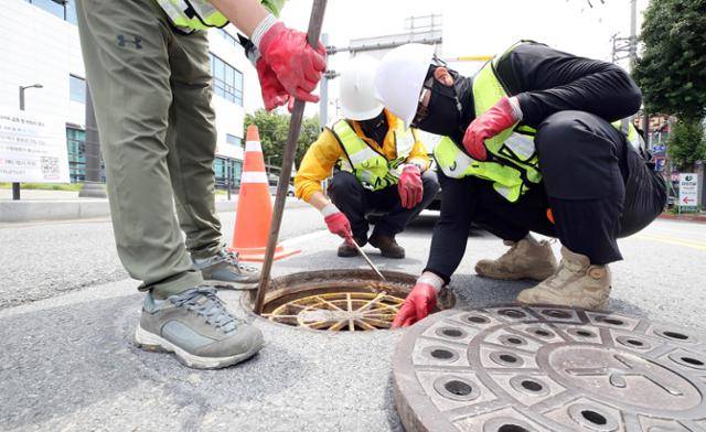 17일 광주 북구 용봉동의 한 교차로에서 북구 하천방재과 하수팀 직원들이 추락사고를 사전 예방하기 위해 맨홀 추락방지 안전망을 점검하고 있다. 뉴시스