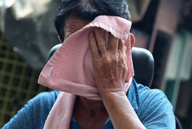 A worker wipes off sweat with a towel while moving materials outdoors near the Dongdaemun Shopping Complex in Jung District, central Seoul, on July 27. [YONHAP]