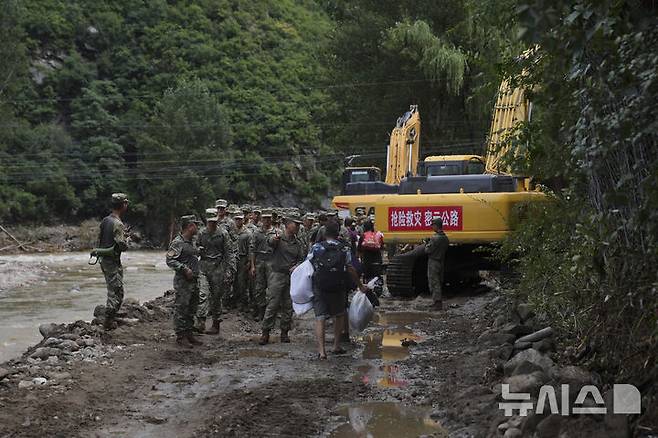 [미원=AP/뉴시스] 29일 중국 베이징 외곽 미원구에 내린 폭우로 홍수가 발생한 뒤 랑자유 마을에서 군인들이 주민들과 대화를 나누고 있다. 2025.07.29.