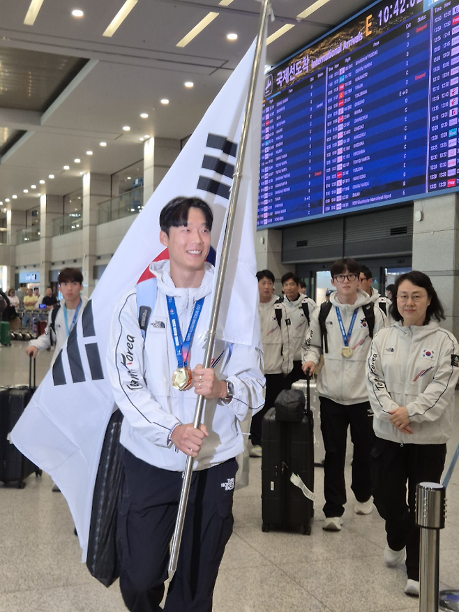 한국 남자 육상 대표 이재성이 29일 태극기를 들고 인천국제공항 1터미널 입국장으로 들어서고 있다. 그는 독일에서 열린 2025 하계 세계대학경기대회에서 금메달과 동메달을 각각 차지했다. 영종도 박성국 기자