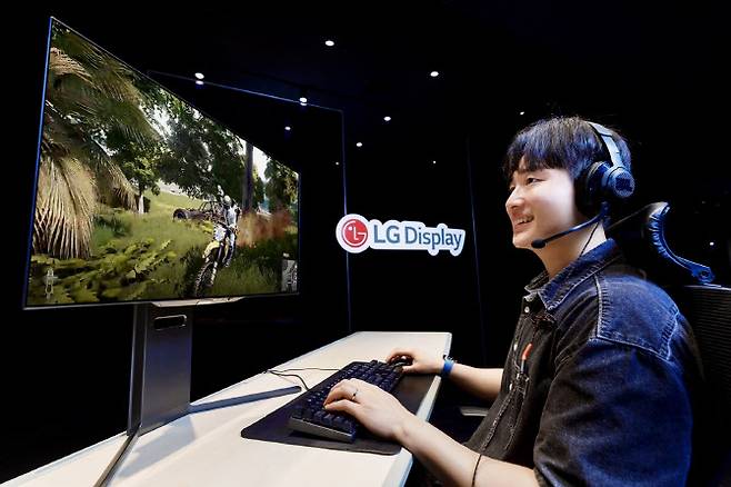 LG디스플레이 모델이 4세대 기술이 적용된 27인치 OLED 모니터 패널로 게임을 즐기고 있다.(사진=LG디스플레이)