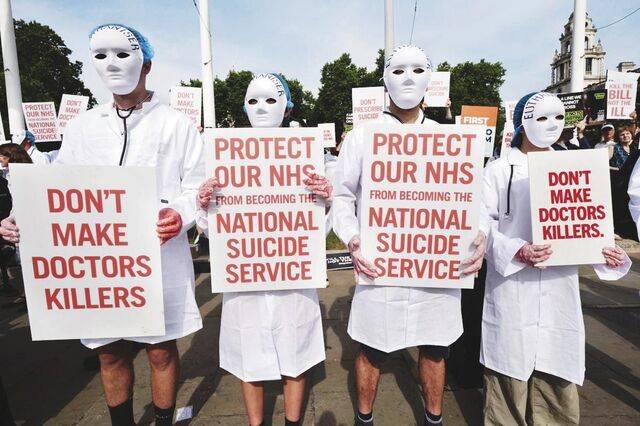 조력 존엄사를 반대하는 시민들이 지난달 20일 영국 런던의 국회의사당 앞에서 ‘의사를 살인자로 만들지 말라’ 등이 적힌 손팻말을 들고 시위를 벌이고 있다. AP연합뉴스