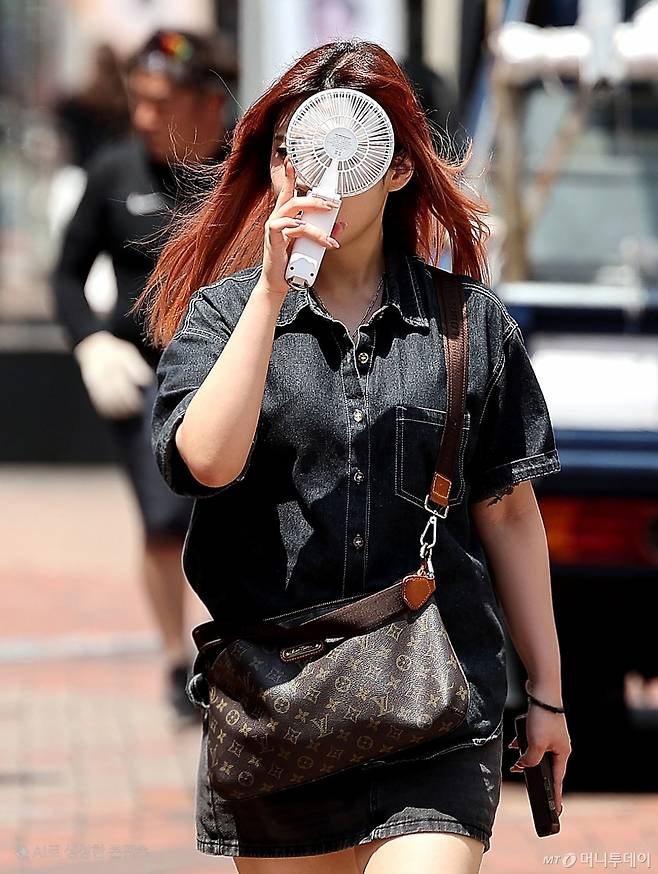 [대구=뉴시스] 이무열 기자 = 폭염이 연일 계속된 23일 대구 중구 동성로에서 한 시민이 손 선풍기를 들고 길을 걷고 있다. 2025.07.23. lmy@newsis.com /사진=이무열
