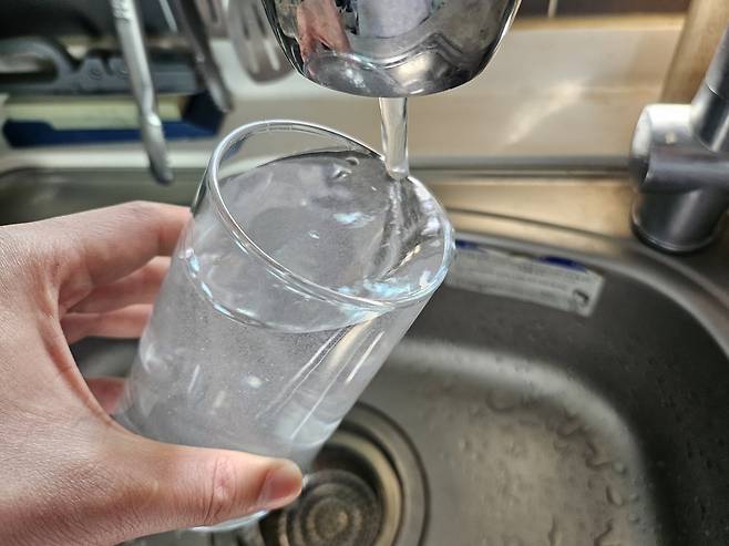 수돗물을 유리잔에 따르고 있다. 김광우 기자.