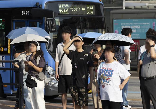 서울 시내 한 버스정류장에서 시민들이 폭염 속 버스를 기다리며 양산을 쓰거나 햇빛을 손으로 가리고 있다. 중복(中伏)인 30일, 서울을 비롯한 전국 곳곳에 폭염 특보가 내려진 가운데 체감온도가 35도를 웃도는 찜통더위가 이어졌다. 뉴시스