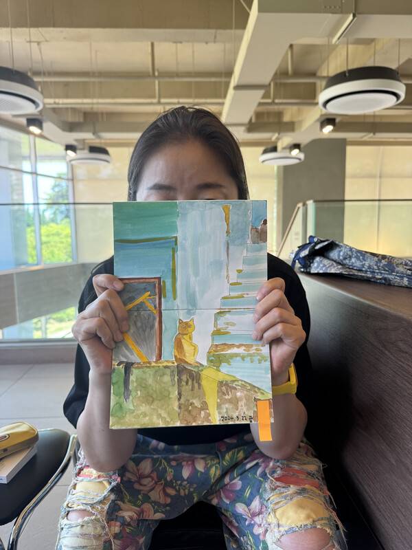 김정우 씨가 자신이 그린 그림을 들고 있다. 그림만큼 화려한 바지가 눈에 들어온다. /이서후 기자&nbsp;