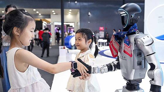 지난 28일 상하이 세계박람회컨벤션센터에서 열린 세계 인공지능 대회(WAIC)에서 한 어린이가 인공지능 기술로 원격 조종되는 휴머노이드 로봇과 악수하고 있다. [AFP=연합뉴스]