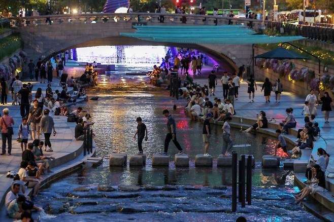 뜨겁고 습한 날씨가 이어지며 열대야 현상 발생이 전망된 지난 30일 저녁 서울 중구 청계천을 찾은 시민들이 물에 발을 담그는 등 산책을 즐기며 무더위를 식히고 있다. /사진=뉴스1