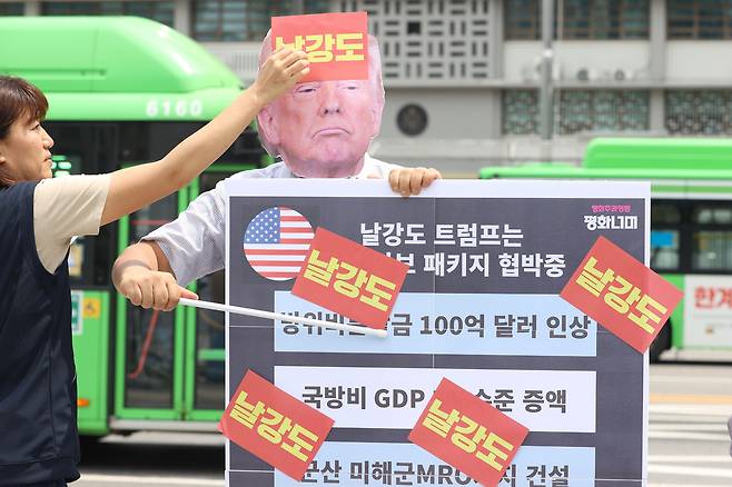 평화주권행동 평화너머 활동가들이 지난 30일 서울 종로구 주한 미국대사관 앞에서 열린 ‘트럼프 관세-안보 패키지수탈 규탄 기자회견’에서 ‘안보비용 수탈과 전쟁동맹 거부 퍼포먼스’를 하고 있다. 연합뉴스