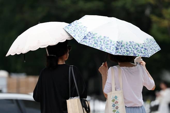 서울에 일주일째 폭염경보가 이어지는 30일 서울 시내의 한 거리에서 시민이 양산을 쓰고 이동하고 있다. 2025.07.30. 뉴시스
