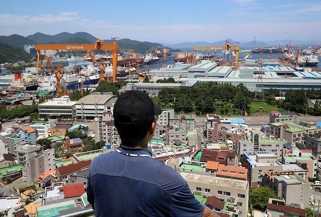 대미 수출 관세 인하와 조선업 투자를 골자로 한 한미 무역 협상이 타결된 7월 31일 한 시민이 경남 거제시 아주동 주거단지 너머로 한화오션 거제사업장 대형 크레인을 바라보고 있다. /뉴스1