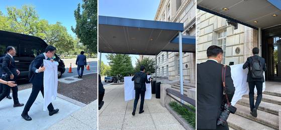 Members of the Korean negotiation team carry a presentation panel wrapped in a hotel tablecloth, with material explaining the ″MASGA″ (Make American Shipbuilding Great Again) project, which is credited with playing a decisive role in breaking the deadlock in the Korea-U.S. tariff negotiations, in front of the U.S. Department of Commerce building in Washington on July 24. [MINISTRY OF INDUSTRY, TRADE AND ENERGY]