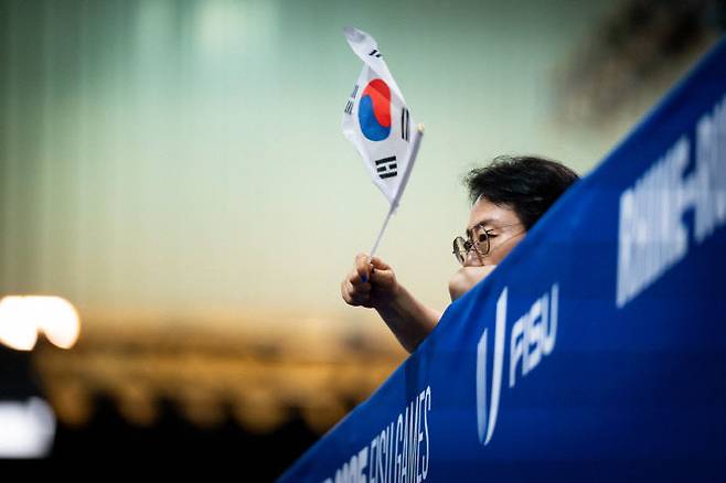 라인-루르 2025 FISU 월드 유니버시티 게임. 탁구 예선에서 한국인이 태극기를 들고 응원하고 있다. 사진=FISU 제공.