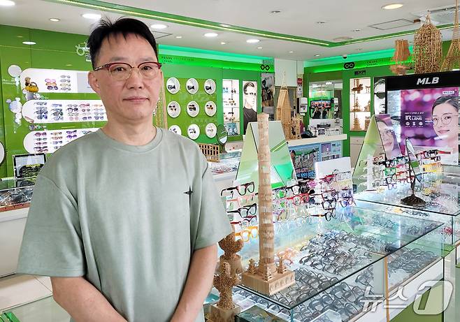 수눌음안경원 사장 여호근 씨. 뒤로 그가 이쑤시개로 제작한 작품들이 보인다.