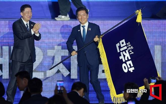 정청래 더불어민주당 신임 당대표가 2일 경기 고양시 킨텍스에서 열린 전국당원대회에서 김병기 당대표 직무대행 겸 원내대표로부터 받은 당기를 흔들고 있다. 김현민 기자