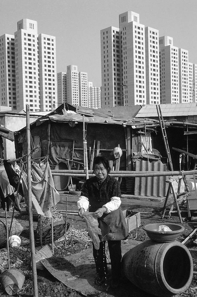 가난한 사람들의 낙후된 판잣집과 대비되는 상하이의 새로 지은 아파트 건물들. 1994년.