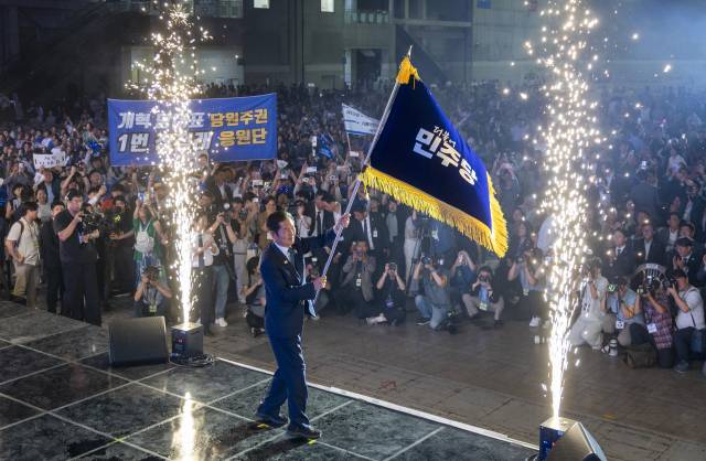 정청래 더불어민주당 신임 당대표가 2일 고양 킨텍스에서 열린 전국당원대회에서 김병기 당대표 직무대행 겸 원내대표로부터 받은 당기를 흔들고 있다. 연합뉴스