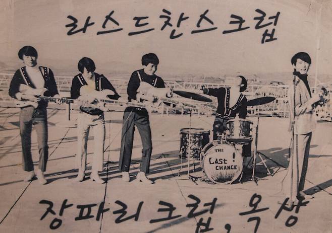 밴드 멤버 다섯 명이 건물 옥상에서 포즈를 취하고 있는 흑백사진. 드럼 세트에 ‘THE AST CHANCE’라고 쓰여 있다.&nbsp;