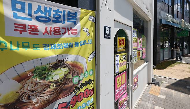 경북 경산시 한 상가에 민생회복 쿠폰 사용처라는 안내 현수막이 붙어 있는 가운데 옆 상가는 폐점한 채 임대 안내문이 붙어있다. [연합]