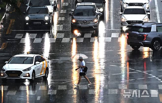 [수원=뉴시스] 김종택 기자 = 수도권 등 중부지역에 호우주의보가 발효된 16일 경기 수원시 팔달구 경수대로에서 한 시민이 우산을 쓰고 이동하고 있다. 2025.07.16. jtk@newsis.com