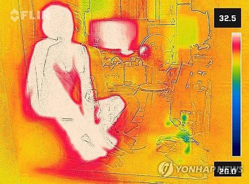 서울 한낮 기온이 34도까지 치솟으며 무더운 날씨를 보인 지난달 24일 서울역 쪽방촌에서 한 주민이 에어컨이 없는 방에서 더위를 견디고 있다. 열화상 카메라 촬영. 온도가 높은 곳은 붉게, 낮은 곳은 푸르게 표시돼 있다. [연합뉴스 자료사진]