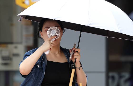지난달 23일 대구 중구 동성로에서 한 시민이 우산과 손 선풍기를 들고 길을 걷고 있다. 뉴시스