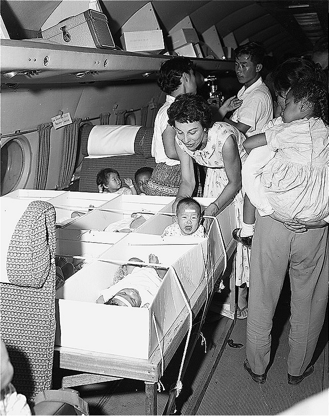 Private adoption agency officials carry babies who are finalized for adoption on to a plane (National Archives of Korea)