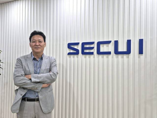 정삼용 시큐아이 대표가 회사 CI를 배경으로 포즈를 취했다. 정 대표는 2022년 1월 대표로 부임했다.