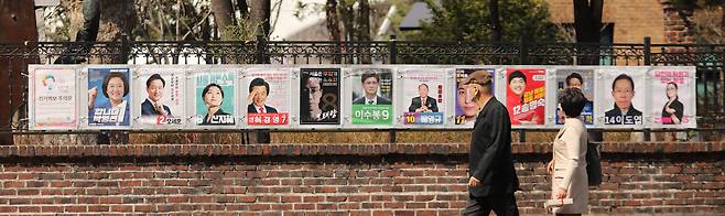 Citizens look at campaign posters for candidates in the April 7, 2021, Seoul mayoral by-election posted on the fence of the Artist’s House in Ihwa-dong, Jongno District, central Seoul. [JOONGANG ILBO]
