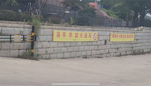 기러기공원 진입로 하천 입구쪽에 설치돼 있는 ‘음주 후 입수금지’ 현수막. 유족 측은 “음주 후 입수금지라는 건, 기본적으로 입수가 가능하나 음주 후에만 금지한다는 내용임을 유추할 수 있다”고 주장했다. [유족 제공]