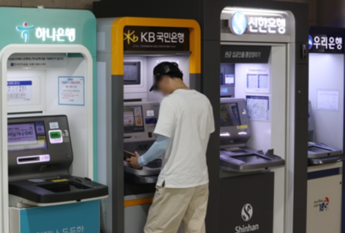 한 건물에 설치된 주요은행 ATM기 모습. 한 고객이 현금을 인출하고 있다. [사진 출처 = 연합뉴스]