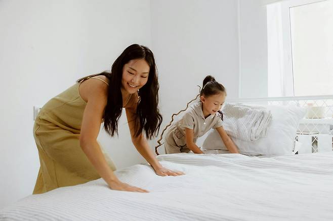 매트리스 커버를 펴고 있는 어른과 아이