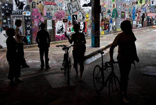 2008년 6월 23일 영국 런던 워털루역 근처의 폐기된 한 터널에서 그라피티 화가 뱅크시가 그린 그림을 행인들이 구경하고 있다. 뱅크시의 그림에 다른 그라피티 화가들의 그림이 더해지면서 이 거리는 런던의 명물로 떠올랐다. /조선DB