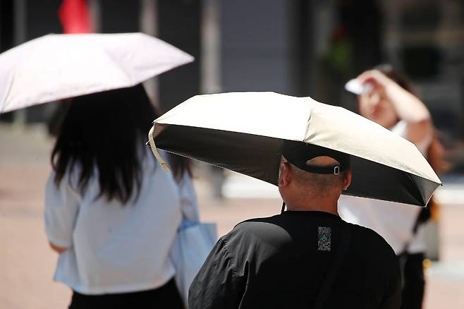 폭염에 성별을 가리지 않고 양산을 펼쳐 든 채 걷고 있다. / 사진=뉴스1