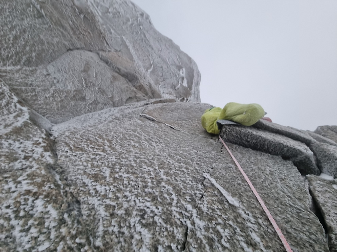 우석주 산악인이 알프스 6대 북벽 중 하나로 꼽히는 ‘프랑스 그랑드조라스’ 를 오르는 과정에서 녹색 침낭에 몸을 맡긴 채 절벽에 매달려 있는 모습. <코오롱인더스트리>