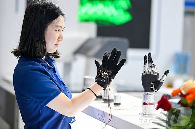 6월 20일 중국 동부 장쑤성 난징에서 열린 2025 세계 반도체 컨퍼런스- 엑스포에서 한 직원이 촉각 장갑을 사용하여 생체공학 팔을 원격으로 제어하고 있다. <자료 사진> 2025.6.20 ⓒ AFP=뉴스1 ⓒ News1 신기림 기자