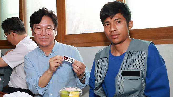 김영훈 고용노동부 장관이 8일 전북 완주군의 한 농가를 찾아 외국인 근로자에게 한글 명찰을 달아주고 있다. /고용노동부 제공