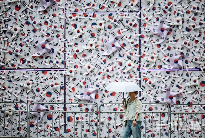 [서울=뉴시스] 정병혁 기자 = 8일 서울 중구 서울광장에 조성된 태극기 언덕 앞에서 한 시민이 이동하고 있다. 2025.08.08. jhope@newsis.com