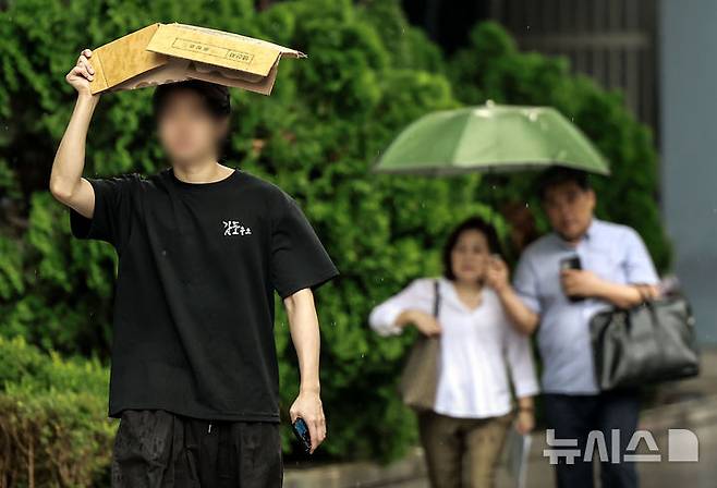 [서울=뉴시스] 정병혁 기자 = 소나기가 쏟아진 8일 서울 중구 청계천 일대에서 한 시민이 박스로 머리를 가린 채 이동하고 있다. 2025.08.08. jhope@newsis.com