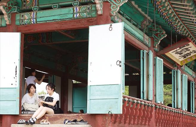 < “K컬처 즐기자” > 8일 경기 수원시 팔달구 수원화성 화홍문을 찾은 중국인 관광객들이 전각 마루에 앉아 휴식을 취하고 있다. 수원화성은 지난해 방영된 인기 드라마 ‘선재 업고 튀어’의 배경으로 등장해 한국 문화와 역사를 즐기러 온 외국인의 인기 여행 코스가 됐다. /문경덕 기자