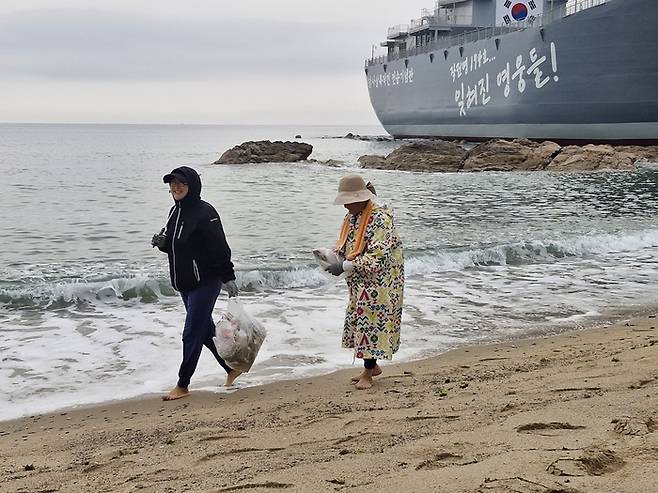 김복강씨(우측)와 막내딸이 지난 9일 새벽 5시쯤부터 영덕 장사해수욕장 모래위에 파도에 밀려온 해안가 쓰레기를 남들 몰래 주워 봉투에 넣은 후  걸어가고 있다.(영남일보 DB)