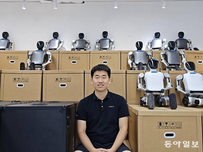 4일 베이징 창핑구 본사에서 휴머노이드 로봇 업체 ‘쑹옌둥리’의 창업자 장저위안(姜哲源)이  배송을 앞둔 로봇들과 함께 기념촬영을 하고 있다. 베이징=김철중 특파원 tnf@donga.com