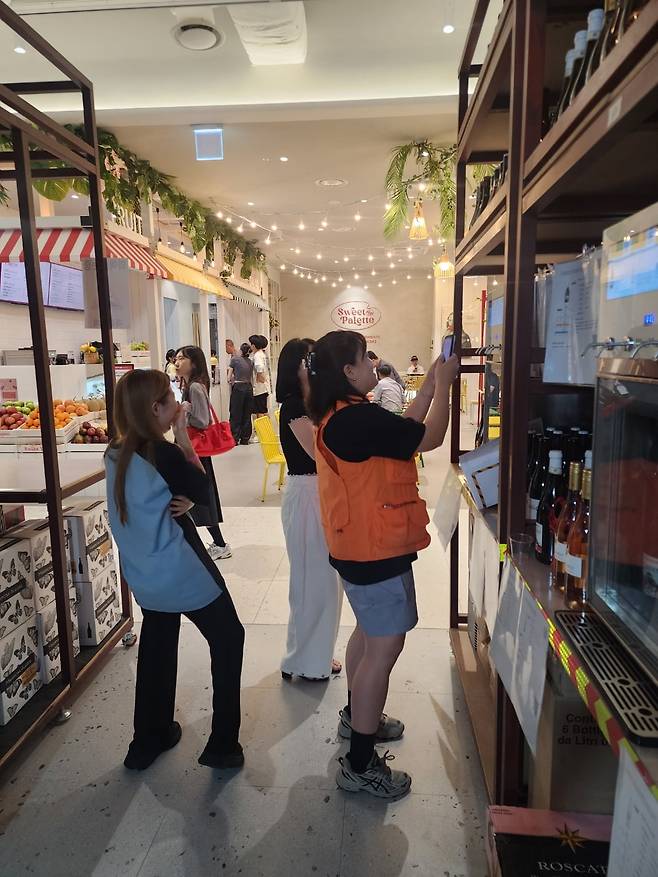 무료 시음 기기를 설명하는 관계자. 시음 기기 앞의 큐알코드를 스캔하면 시음용 와인이 나온다.