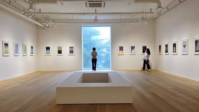 [사진=박현주 미술전문기자]3전시실에 선보인 쇼 시부야의 작품. '뉴욕 타임스' 신문 36점이 질서 있게 걸려 있다. 한쪽 벽면에는 총격 사건과 전쟁, 재난과 참사의 소식들이 압축된 색면으로 기록되어 있고, 마주한 벽면에는 같은 날 아침의 광활하고 고요한 하늘 풍경이 펼쳐진다. 관객은 힌지로 설치된 액자를 넘기며 채색된 화면과 원본 신문을 번갈아 볼수 있다. *재판매 및 DB 금지