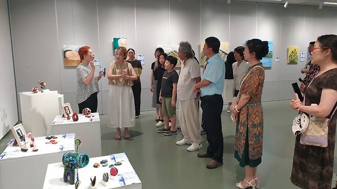 ▲ 2025 한중교류 프로젝트 'WeiHai 예술교감' 전시가 열린 중국 웨이하이 천화미술관에서 업싸이클 환경 관련 작품을 선보인 전희상(왼쪽) 작가가 작품을 설명하고 있다./사진제공=이루